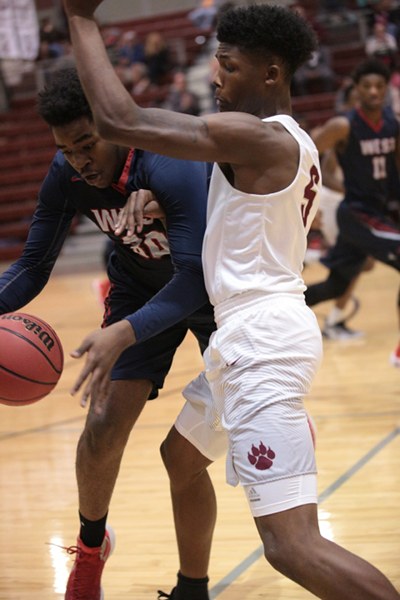 Oak Ridge senior Tee Higgins plays defense against West senior forward Tyrone Patterson (30) during a 68-38 Region 2-AAA quarterfinal win against West at home on Saturday, Feb. 25, 2017. (Photo by Luther Simmons)