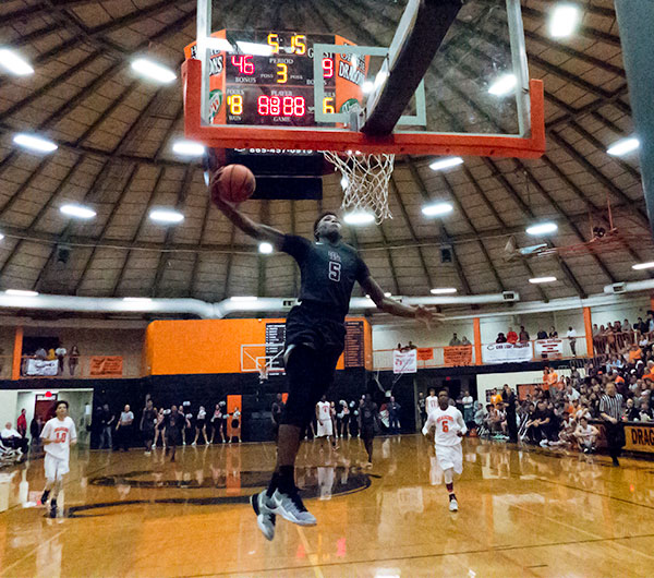 After crossing the ball between his legs from his left hand to his right, Oak Ridge senior Tee Higgins (5) slams it through the basketball hoop with his right hand during a 111-77 semifinal win at Clinton in the District 3-AAA tournament on Saturday, Feb. 18, 2017. (Photo by John Huotari/Oak Ridge Today)