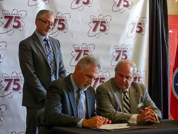 Oak Ridge Mayor Warren Gooch, seated at right, and UCOR President and Project Manager Ken Rueter, also seated, sign a license that allows UCOR, the federal cleanup contractor in Oak Ridge, to start construction of the K-25 History Center on the second floor of the city-owned Fire Station Number Four at East Tennessee Technology Park on Thursday, Oct. 19, 2017. Also pictured standing is Jay Mullis, acting manager of the U.S. Department of Energy's Oak Ridge Office of Environmental Management. (Photo by John Huotari/Oak Ridge Today)