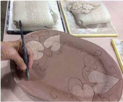 After pressing real leaves into wet clay, Scottie Baxter carves in the vining stems. (Submitted photo)